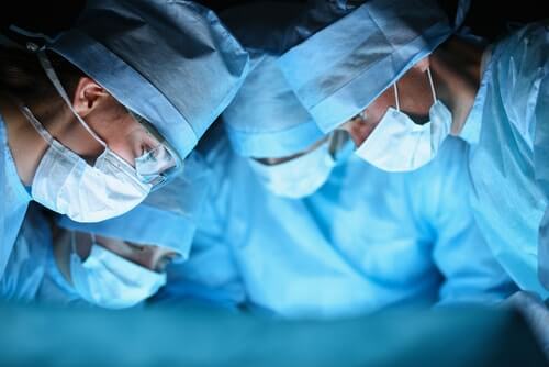 Surgeons Gathered Closely, Working On Patient With Patient Out of Shot